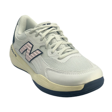 New Balance ladies pickleball shoe. Suitable for tennis, pickleball and netball. Has a white mesh upper with a pink N and Navy heel and sole.
