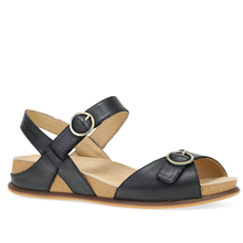 A black leather sandal with adjustable ankle and instep straps, featuring gold-tone metal buckles, a cork midsole, and a brown outsole.