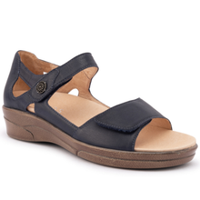 The Klouds Effie sandal. A navy blue leather wedge sandal with a hook-and-loop strap closure and a decorative metal button. has two straps and a supported heel.