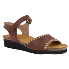 A brown leather wedge sandal with a supportive cork midsole and black outsole, featuring decorative cream stitching on the front strap.