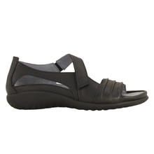 The Noat Papaki. A women's open-toe slip-on sandal in black, featuring a black wedge sole and a wide adjustable strap with a velcro closure. Mae with a cork and latex removable insole.